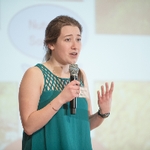 Woman presenting her thesis, one hand gesturing as she speaks into a microphone